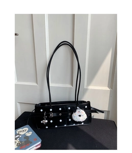Detail of black polka dot underarm bag with silver heart charm and plush pendant