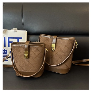 Comparison of brown quilted suede bucket bags in two sizes on black leather sofa