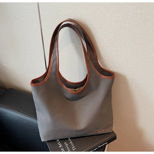 Detail of grey canvas tote bag with brown faux leather trim and magnetic closure