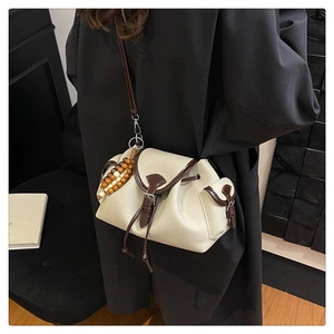 Dettaglio di borsa a tracolla intrecciata beige con finiture in pelle marrone e perline