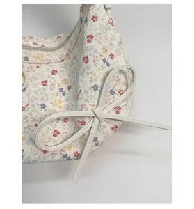 Gros plan d'un sac à fleurs blanc avec nœud en cuir décoratif et imprimé floral coloré