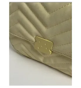 Detail der cremefarbenen Stepptasche mit V-Nähten und goldenem quadratischem Schloss