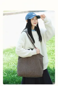 Detail of a large houndstooth tote bag in a casual autumn outfit with a knit sweater