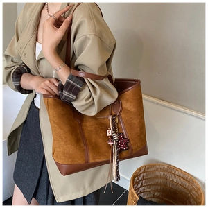 Detail of caramel suede and leather patchwork tote bag with heart charm accessory