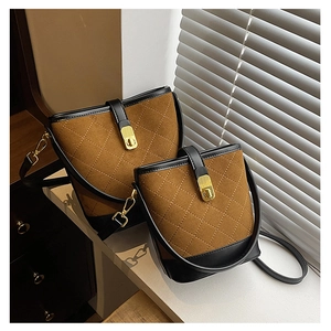 Detail of quilted caramel brown bucket bags with gold twist locks on a window sill