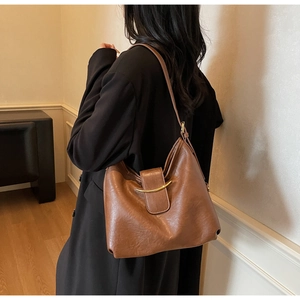 Detailed view of deep brown faux leather hobo bag with a gold metal buckle on a shoulder strap