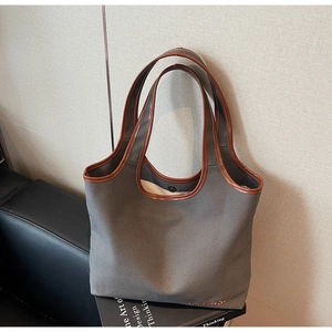 Detail of grey canvas tote bag with brown leather trim and subtle embroidery accent