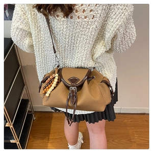Dettaglio borsa a tracolla vintage marrone con patta in pelle e ciondolo in perle di legno