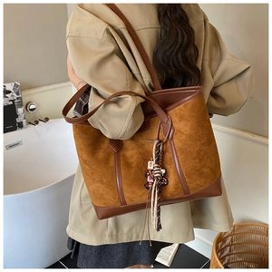Detail of tan suede tote bag with leather trim and woven tassel for daily work wear