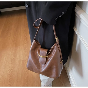 Detailed close-up of brown vintage leather bucket bag with gold crescent metal buckle