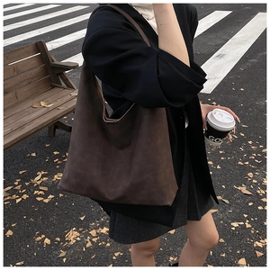 Detail view of a large brown suede hobo bag styled for autumn city commuting scenes