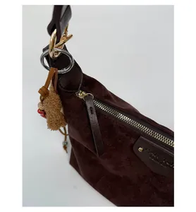 Macro shot of smooth gold zipper and suede texture on dark coffee shoulder bag