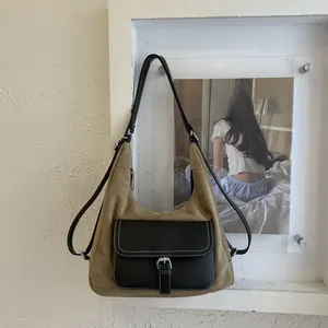 Detail of vintage suede hobo bag with leather pocket and metallic buckle closure
