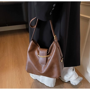 Detail of vintage brown tote bag with smooth texture and golden crescent moon buckle