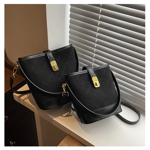 Close-up of black quilted bucket bags with suede texture and gold turn-lock hardware