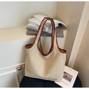 Detail of canvas tote bag with brown leather trim and TaoCaitu logo embroidery