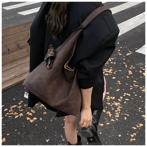 Street style view of a dark brown Hobo tote bag with leopard print accessory