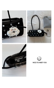 Detail view of black polka dot handbag with plush puppy charm and silver zipper closure