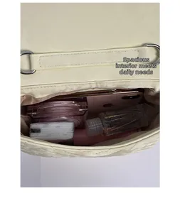 Makroansicht des Innenraums einer cremefarbenen gesteppten Tasche mit Silberteilen