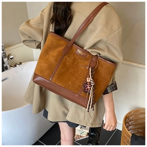 Detail of caramel tote bag featuring suede patchwork and metallic fashion logo lettering