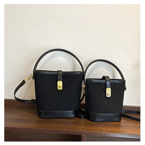 Detailed comparison of large and small quilted black bucket bags on a wooden shelf