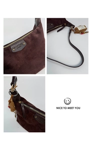 Detailed close-up of dark brown suede shoulder bag with leather trim and gold hardware