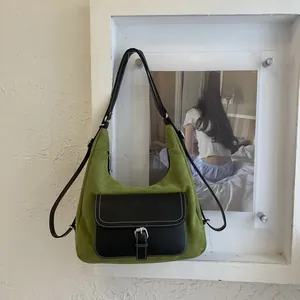 Detail of green suede shoulder bag with black leather pocket and white contrast stitching