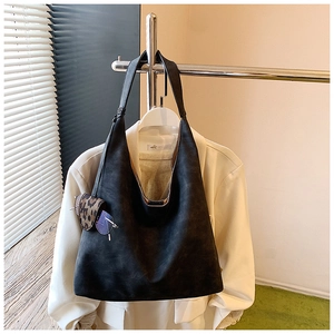 Detail of black suede hobo bag with silver hardware and a leopard print charm accessory