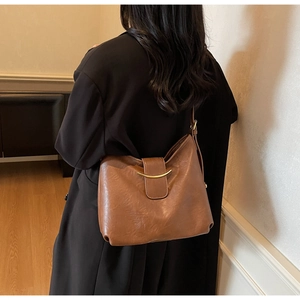 Detail of the golden crescent moon buckle on a vintage brown leather tote shoulder bag