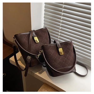 Detail of dark brown quilted suede bucket bags with gold hardware in natural light