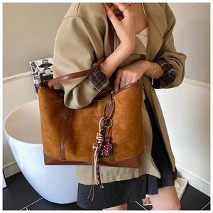 Close-up of brown suede tote bag with leather trim and decorative silk scarf detail