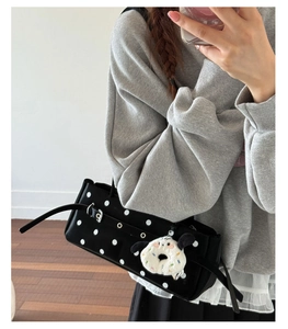 Close-up of retro polka dot handbag with metal eyelet strap and plush charm