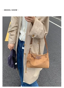 Sac bandoulière en daim marron avec porte-clés ours, porté par un mannequin