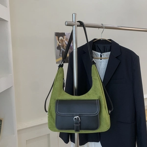Detail of olive green suede shoulder bag with black leather pocket and white contrast stitching
