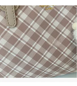 Λεπτομέρεια καρό τσάντας σε καφέ και λευκό με χρυσό λογότυπο και λούτρινο διακοσμητικό