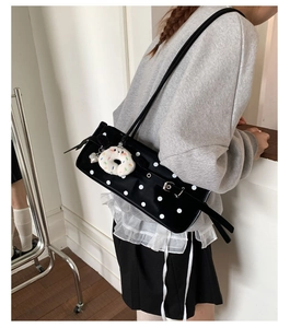 Close-up of vintage black polka dot shoulder bag with white fluffy donut pendant