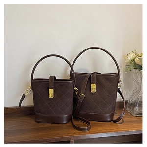 Detail of dark brown quilted bucket bags in large and small sizes on a wooden desk