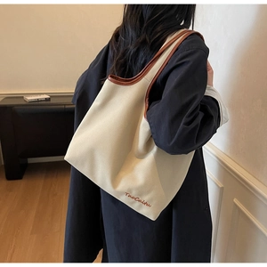 Detail of high-density canvas tote with leather shoulder straps and orange logo embroidery