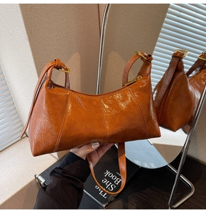 Détail d'un sac à bandoulière en cuir ciré marron brillant avec fermeture éclair dorée