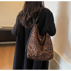 Detail of leopard print tote bag with black shoulder strap and golden hardware on a coat