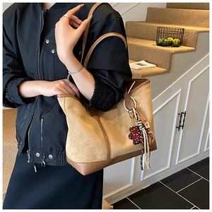 Detail view of khaki suede tote bag with leopard bear charm and brown leather trim