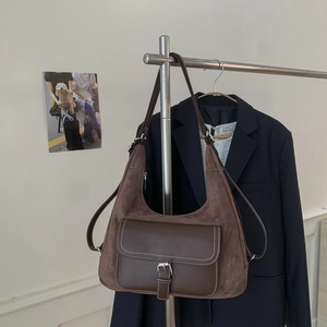 Detail of dark brown hobo bag with contrast stitching and silver buckle on suede surface