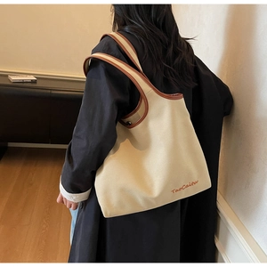 Detail of canvas tote bag with brown leather trim and fine TaoCaitu letter embroidery