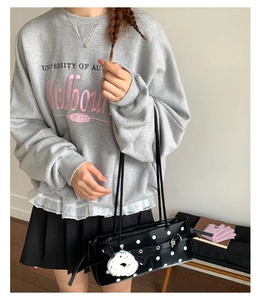 Detail of black patent leather underarm bag with white polka dots and plush Snoopy charm