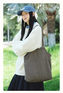 Outdoor lifestyle shot of a large houndstooth tote bag styled with a winter sweater
