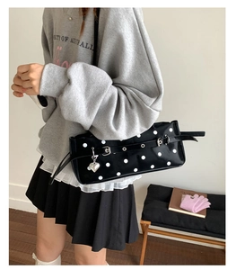 Detail of black polka dot baguette bag with silver heart charm and adjustable strap