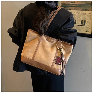 Detail of khaki suede tote bag with brown leather trim and cute bear charm accent