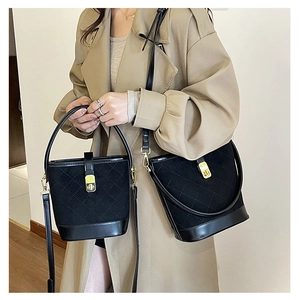 Detail of black quilted bucket bags in two sizes with gold hardware and leather strap