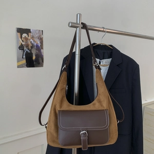 Detailed view of vintage brown suede hobo bag with leather pocket on a suit background
