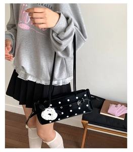 Detailed side view of vintage polka dot baguette bag with plush puppy keychain